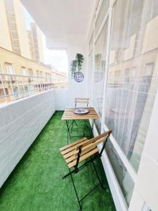 una mesa y una silla en un balcón con césped verde en Evangelista59 en Sevilla