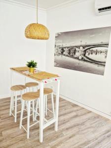 una mesa blanca y taburetes en una habitación con una pintura en Evangelista59, en Sevilla