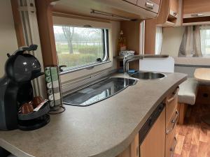 a kitchen with a sink and a window in an rv at CAMPING LES HERLEQUINS in Losne