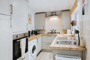 - une cuisine blanche avec un évier et un lave-vaisselle dans l'établissement 3 Bed - Modern Comfortable Stay - St Helens Town Centre, à St Helens