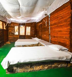 two beds in a room with wooden walls at Tree House Rangala in Hunnasgiriya