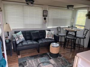 a living room with a black couch and a table at Rustic Farm meadow stay in Temecula