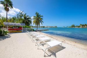 a row of white lounge chairs on a beach at Flip Flop Kai home in North Side