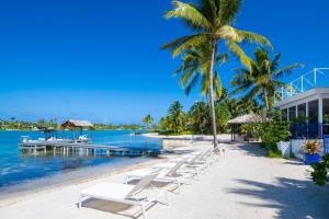 a beach with white lounge chairs and a dock at Flip Flop Kai home in North Side