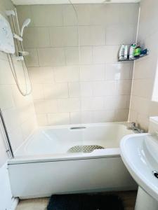 a white bathroom with a tub and a sink at Quiet Single bedroom with free parking, office desk &chair, free wifi in Harrowden