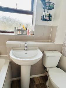 a bathroom with a sink and a toilet and a window at Quiet Single bedroom with free parking, office desk &chair, free wifi in Harrowden