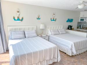 two beds in a room with white walls at Beachfront Studio - Perfect Location - Free Beach Chairs in Panama City Beach