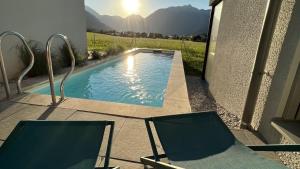 2 chaises et une piscine sur une terrasse dans l'établissement TIROLER TRIS Chalet & Penthouse, à Maurach