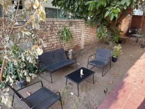 three chairs and a table in front of a brick wall at Hostal EntreOrientes in Viña del Mar