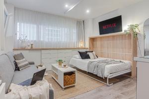 a bedroom with a bed and a living room with a couch at Super Centro y Playa by TheBlueWaveApartments com in A Coruña