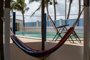 a hammock and a chair next to a pool at Tahiti Hotel in Cotonou