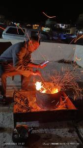 a person standing next to a pot with fire at Petra Magic Guest House in Wadi Musa