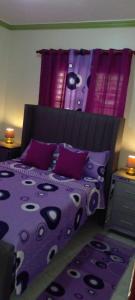 een bed met een paars dekbed en kussens bij Maria e Nicola in Jarabacoa