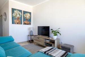 a living room with a blue couch and a tv at Blue House in Santa Cruz with Sea View in Santa Cruz