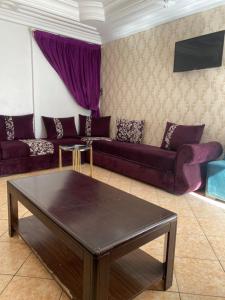 una sala de estar con sofás morados y una mesa. en Hotel Merry en Agadir