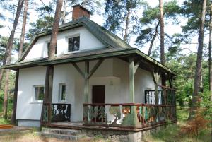 an old house with a wrap around porch in the woods at Domyletnie Pobierowo Duży dom 140m2 z działką in Pobierowo
