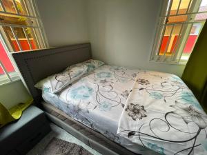 - un petit lit dans une chambre avec 2 fenêtres dans l'établissement Villa Ingracia" Rustig omgeving waar je wakker wordt van de mooie vogelgeluiden", à Paramaribo