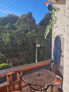 a table and chair on a balcony with a fence at Piemonte Flat Serra Negra in Serra Negra