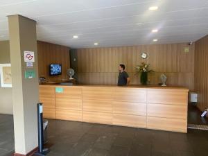a man standing at a reception desk in an office at Piemonte Flat Serra Negra in Serra Negra