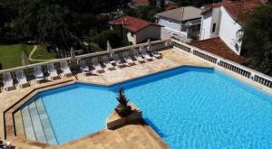 a large blue swimming pool with lounge chairs and sidx sidx sidx at Piemonte Flat Serra Negra in Serra Negra