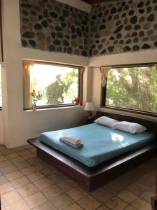 a bedroom with a large bed with two windows at Jungle River Lodge in La Ceiba