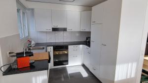 eine Küche mit weißen Schränken und einer schwarzen Arbeitsplatte in der Unterkunft Apartment Cindy in Spiez
