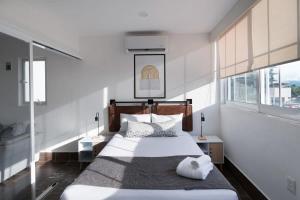 1 dormitorio con 1 cama grande, paredes y ventanas blancas en 2 BR Penthouse Condo Puerto Vallarta, en Puerto Vallarta
