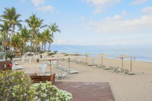 a beach with chairs and umbrellas and the ocean at 1BR one block away to a beautiful beach in Puerto Vallarta