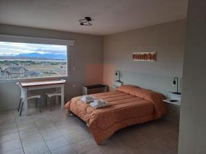 Schlafzimmer mit einem Bett, einem Schreibtisch und einem Fenster in der Unterkunft Go Patagonia! in El Calafate