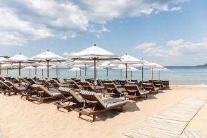 een groep stoelen en parasols op een strand bij Vouliagmeni Garden Suite by Astir beach in Athene