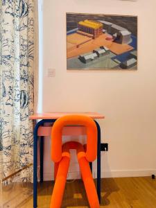 a table with an orange chair in front of a painting at Maison Georges in Tourcoing