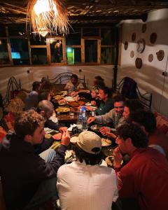 Un groupe de personnes assises autour d'une table et mangeant de la nourriture dans l'établissement Red Carpet Surf Camp, à Tamraght Ouzdar
