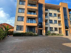 duży budynek apartamentowy z ceglanym parkingiem w obiekcie KAVOD FURNISHED APARTHOTELS w mieście Kampala