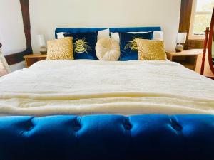uma cama azul com almofadas em cima em Log Burner and Beamed Ceilings-2 Bed Cottage Crumpelbury and Whitbourne Hall less than a 4 minute drive Dog walking trails and local pub within walking distance and a 30 minute drive to the Malvern Hills em Worcester