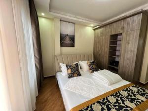 sypialnia z dużym łóżkiem z białą pościelą i poduszkami w obiekcie KAVOD FURNISHED APARTHOTELS w mieście Kampala