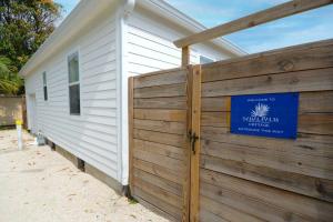 a building with a fence with a blue sign on it at Sabal Palm Vacation Homes in Lake Worth