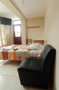 ein Schlafzimmer mit einem Bett und einem schwarzen Stuhl in der Unterkunft Hospedaje Cruz Oxapampa in Oxapampa