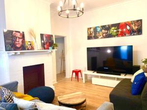 a living room with a fireplace and a large screen tv at Lux 4BR Straithfield house close 2 airport/city in Sydney