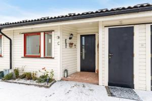 a white house with a black door and a window at Cozy and central home near Oslo Gardermoen Airport in Eidsvoll