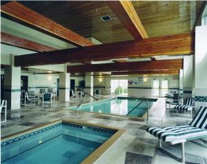 een zwembad in een gebouw met stoelen en een tafel bij Holiday Inn Express & Suites Port Washington, an IHG Hotel in Port Washington