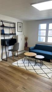 sala de estar con sofá azul y 2 mesas en Charmant studio place Stanislas, en Nancy