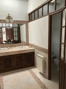 a bathroom with two sinks and a mirror and a toilet at Casa rural Santa María del Castillo in Olivenza