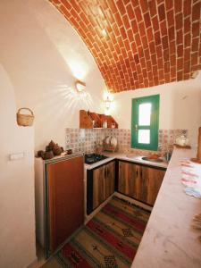 eine Küche mit Holzschränken und einer Ziegeldecke in der Unterkunft Douira S+1 in Chebba