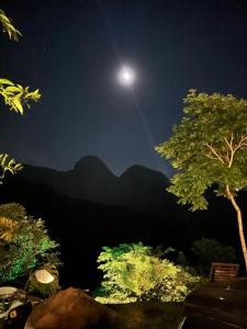 una vista a la luz de la luna de un árbol y montañas por la noche en O Chalé mais bucólico de Araras. Vista linda, en Petrópolis