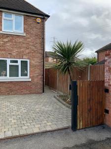 a brick house with a wooden fence and a palm tree at Beautiful 4 Bed House Free WIFI in Earley