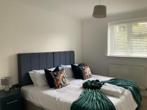 a bed with a blue headboard in a bedroom at Beautiful 4 Bed House Free WIFI in Earley