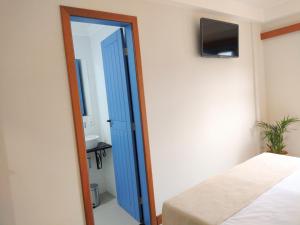 a bedroom with a blue door leading into a bathroom at Pousada VilaZinha in Vila Velha