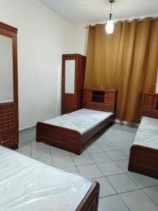 Cette chambre comprend 2 lits et un miroir. dans l'établissement شقق مفروشة Apartment 2 Bedroom Majaz3, à Charjah