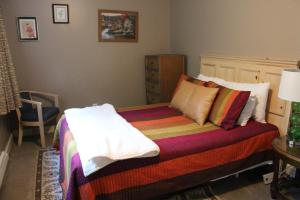 een slaapkamer met een bed met kleurrijke dekens en kussens bij Cliff Dwellers Inn in Blowing Rock