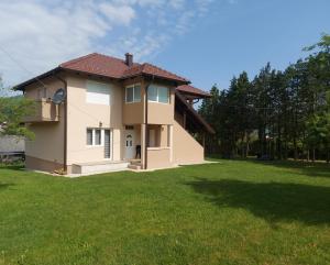 ein Haus mit grünem Rasen davor in der Unterkunft Apartman Feniks in Plijeskovo